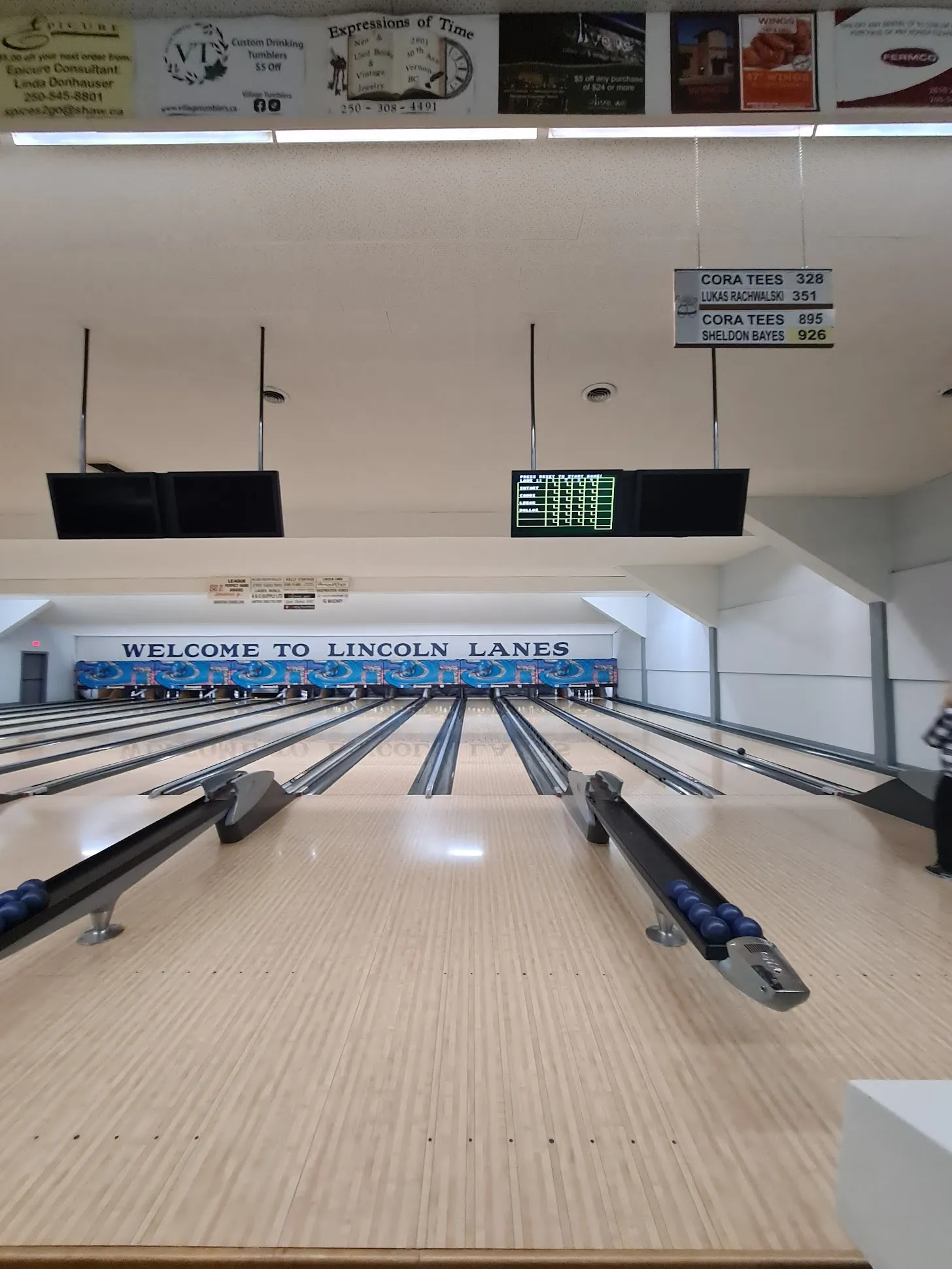 The lanes and overhead score monitors showing league standings at Lincoln Lanes